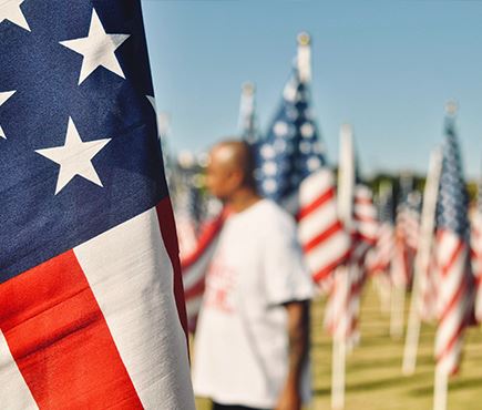 A man walks through a memorial of American flags