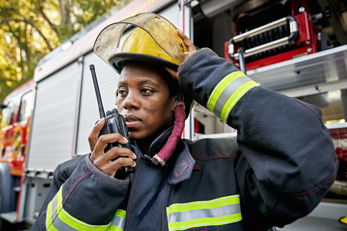 Firefighter stands by firetruck speaking on walkie talkie