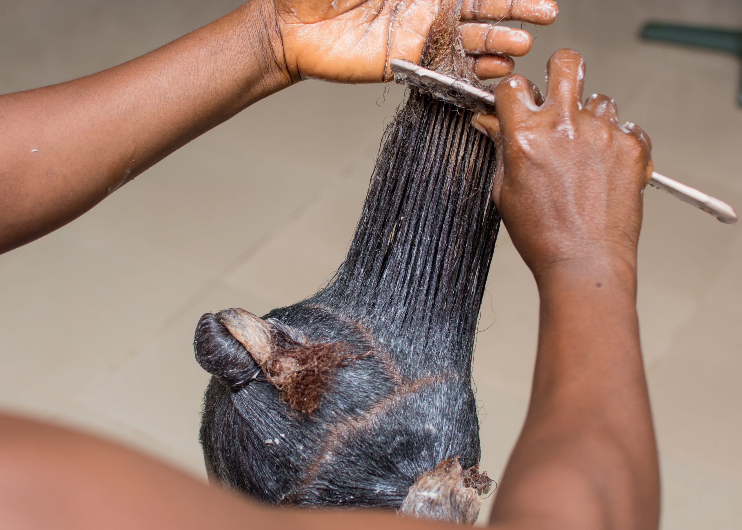 Hair relaxer being applied and combed through hair